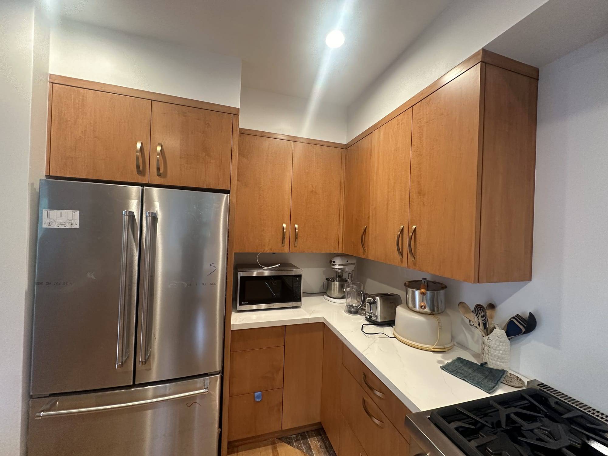 Natural wood stained kitchen cabinets beside the refrigerator