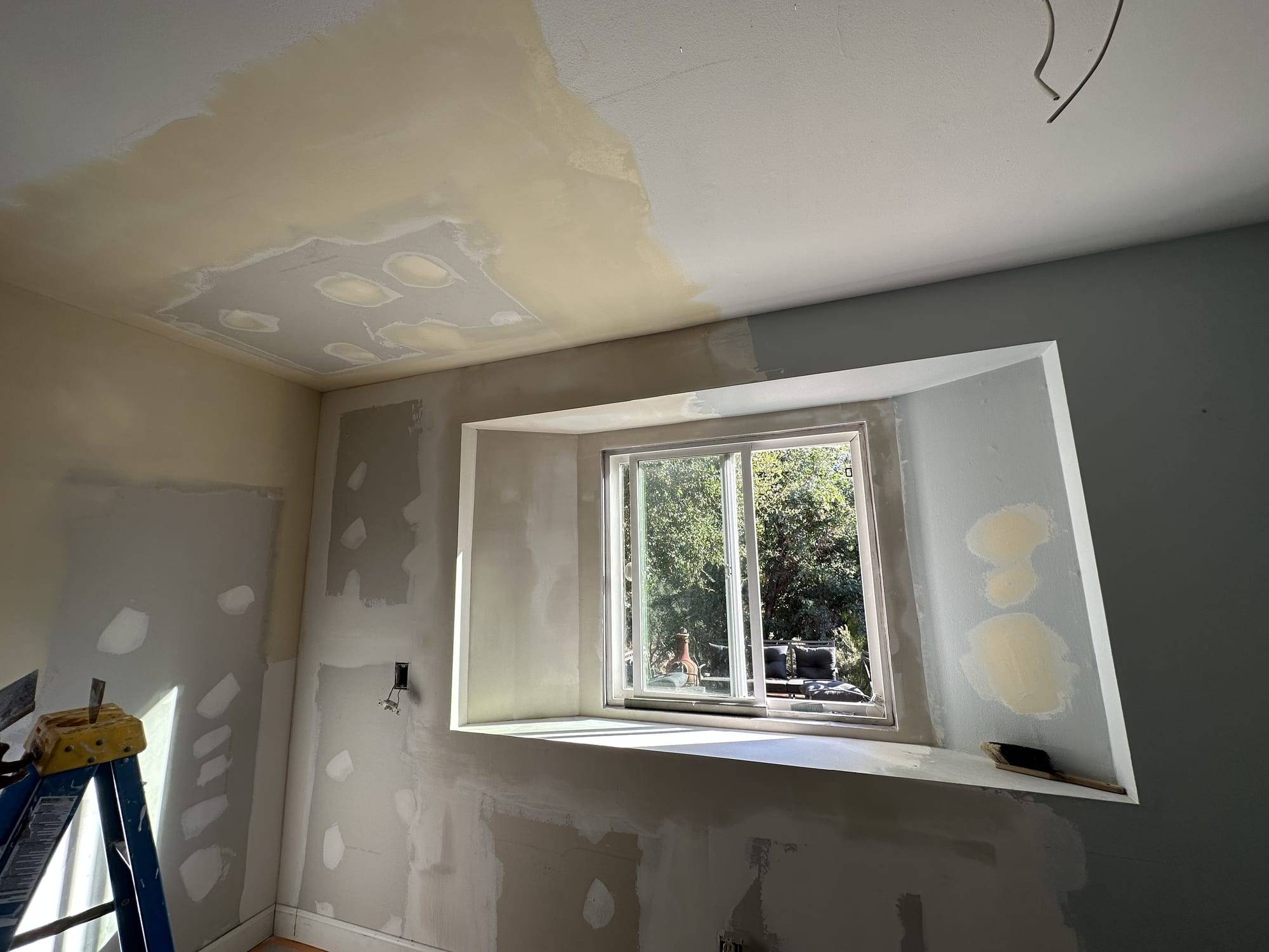Drywall patches on a bedroom window wall and ceiling