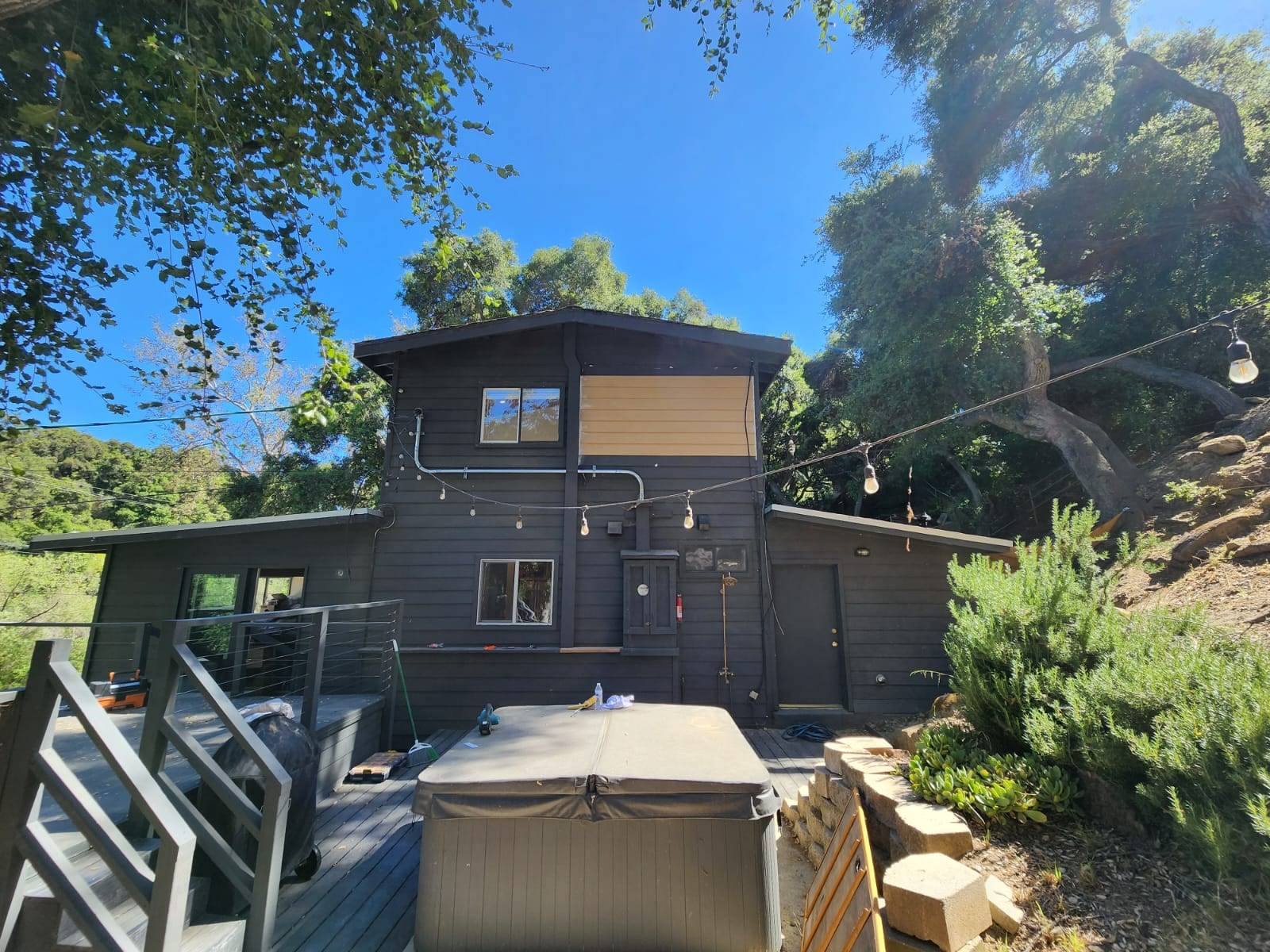 Hillside home mid-repaint in charcoal siding