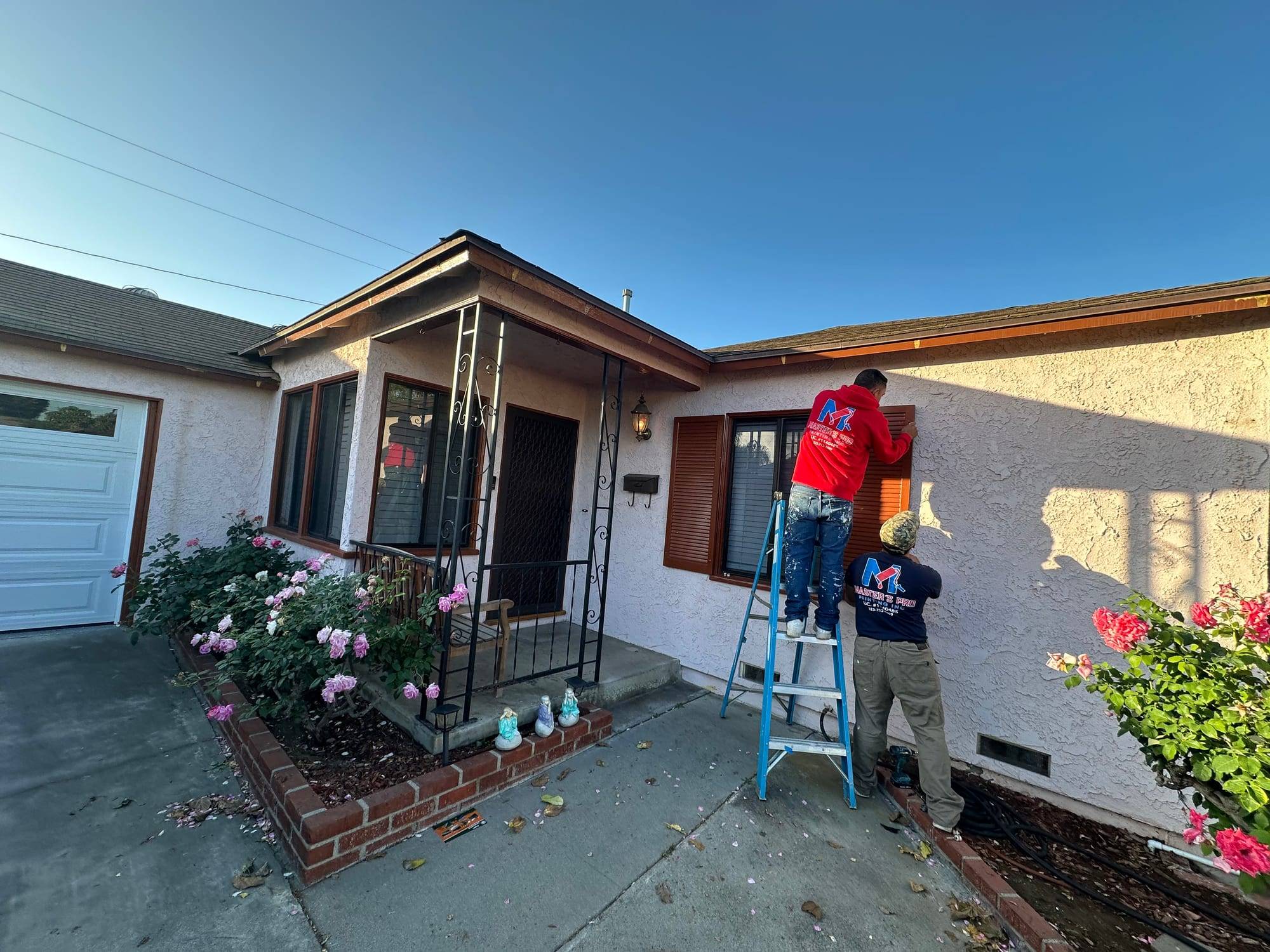 Master's Pro Painting crew on a ladder painting window shutters