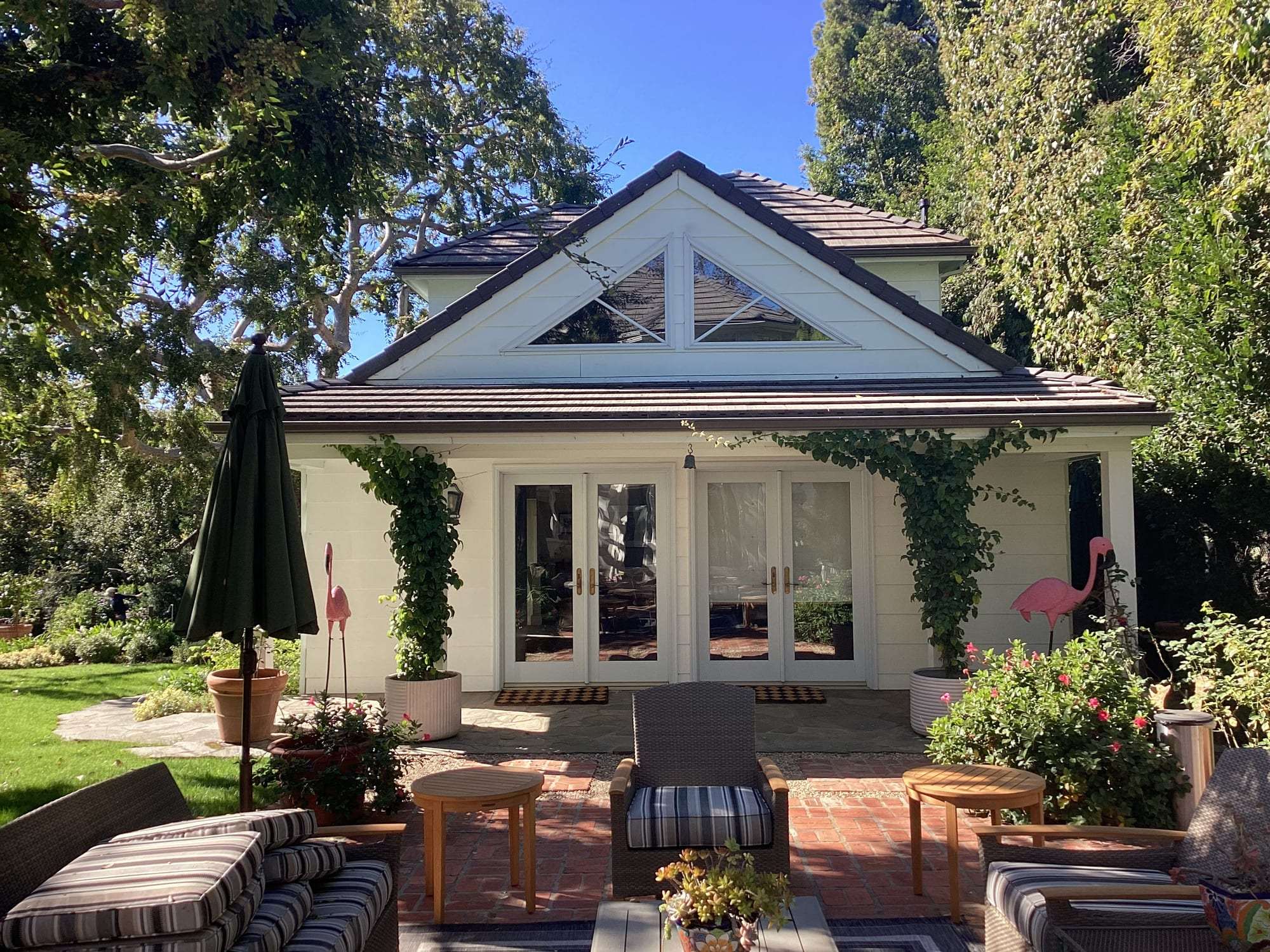 Freshly painted white garden cottage exterior with French doors and patio