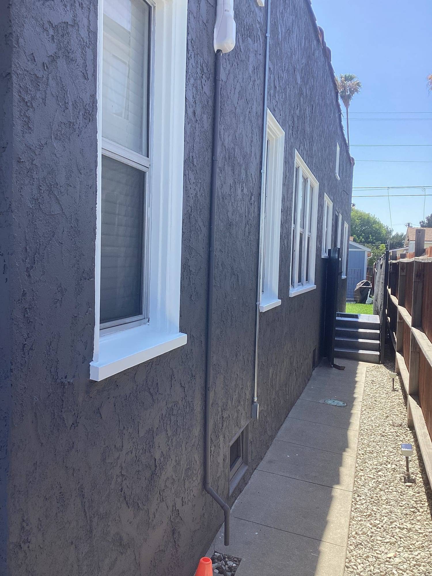 Gray stucco side wall with freshly painted white window trim