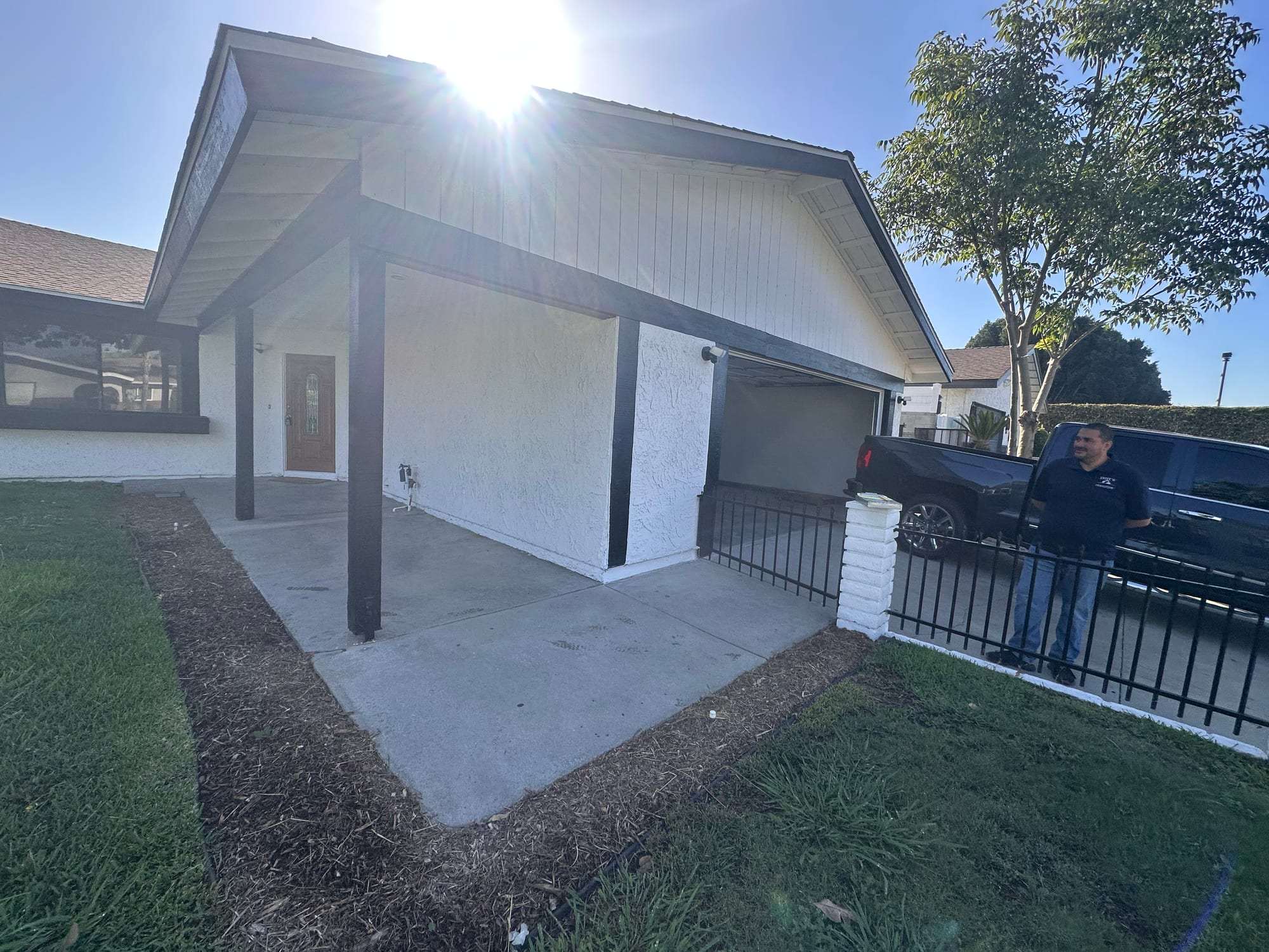 White stucco home with dark painted carport posts and fascia
