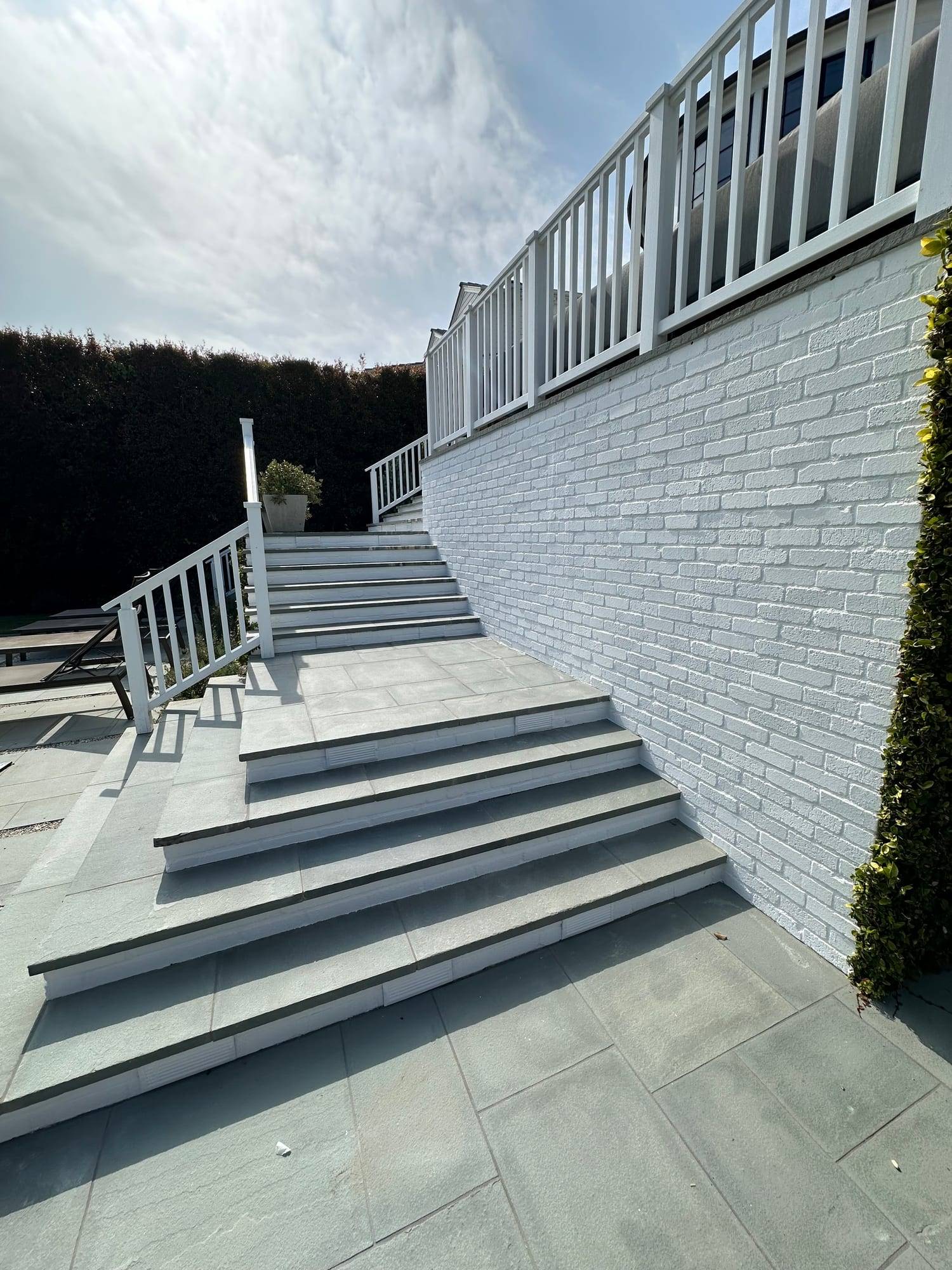 White painted brick wall beside gray stairs and white railings
