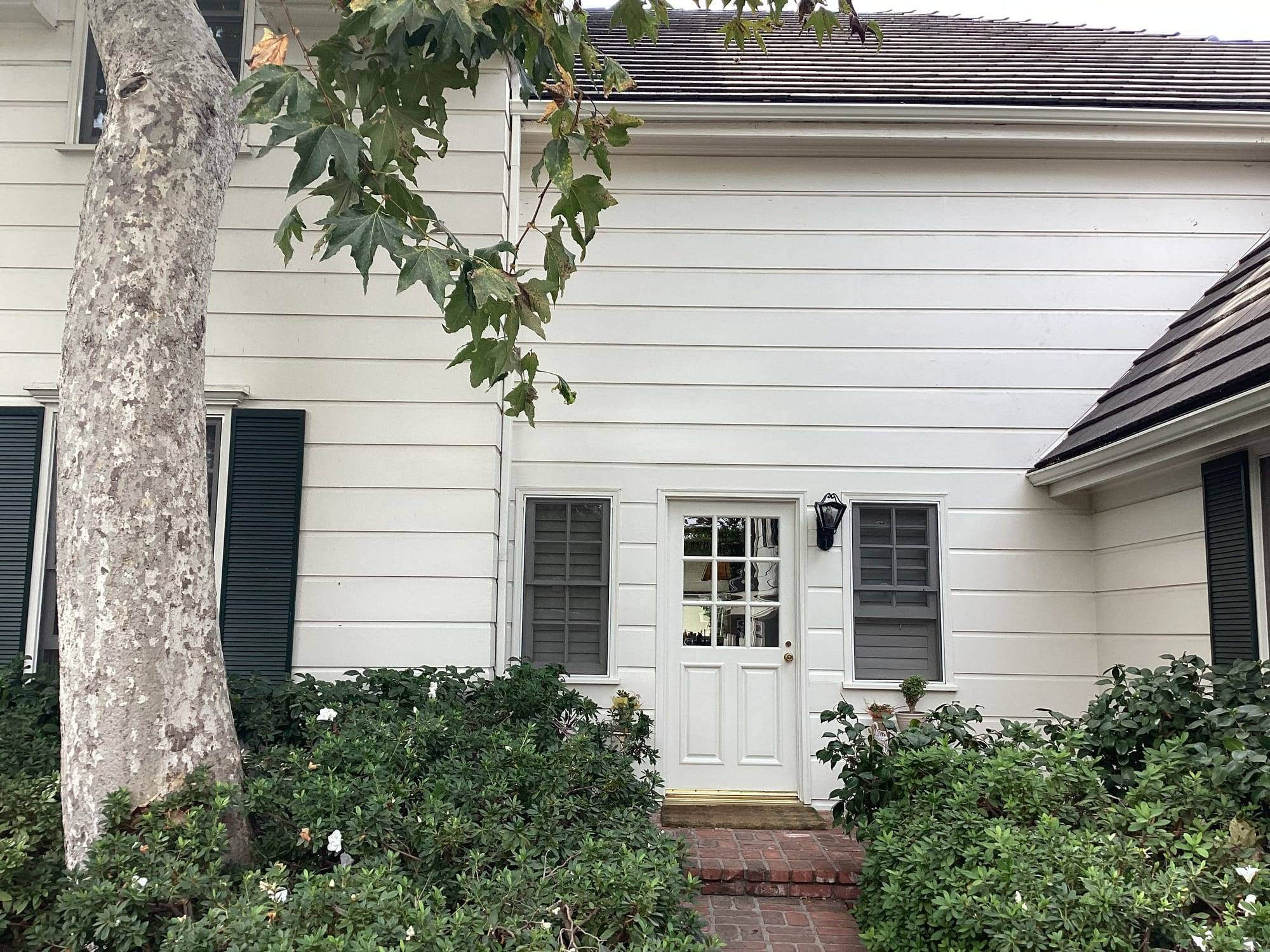 White lap siding home with dark green shutters and a white entry door
