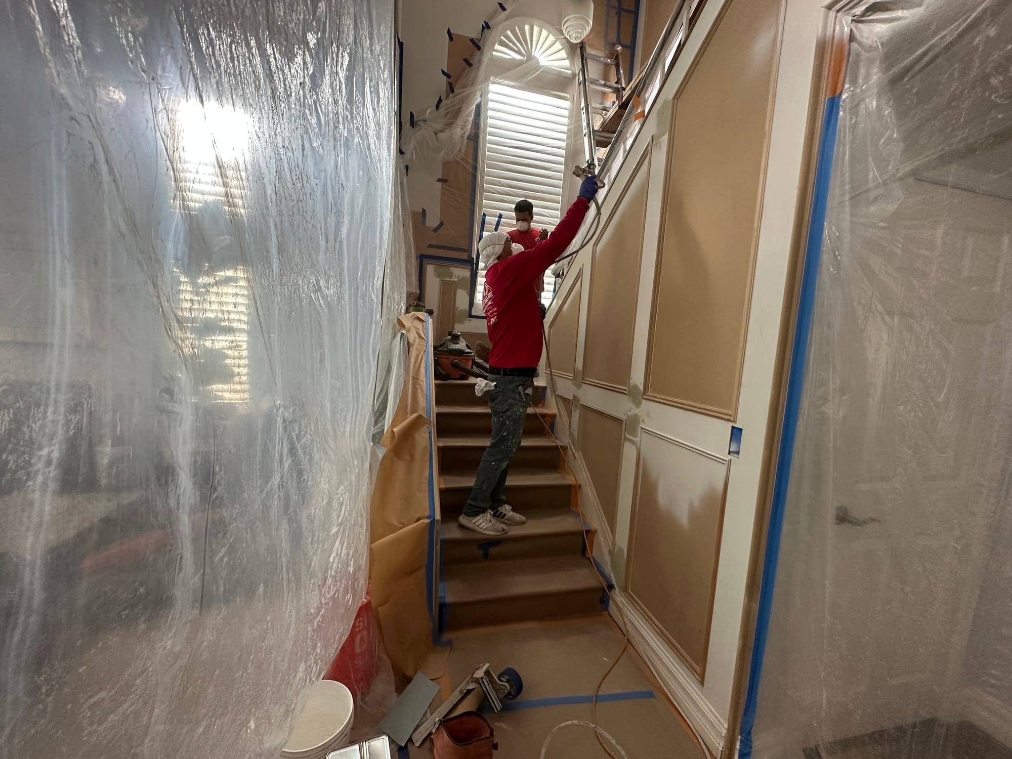 Master's Pro crew spraying a paneled stairwell with the room sealed in plastic