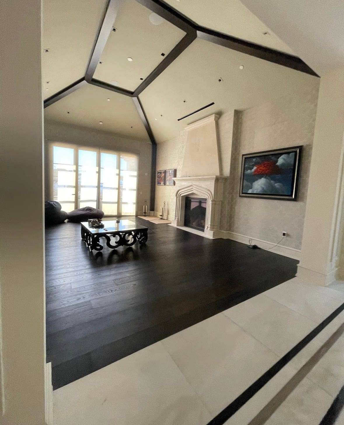 Finished living room with a vaulted beamed ceiling and a stone fireplace