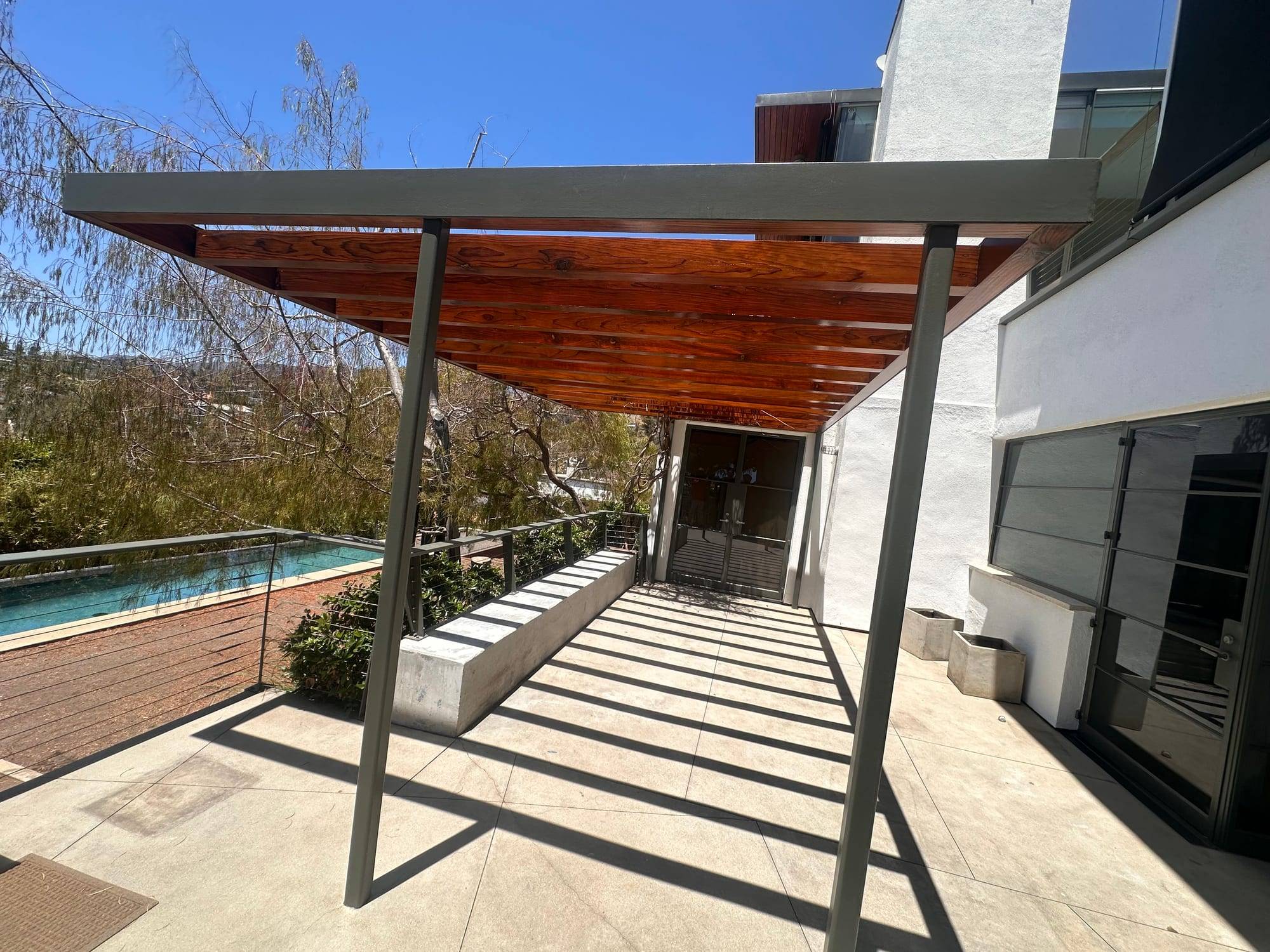 Stained wood pergola ceiling over a modern patio